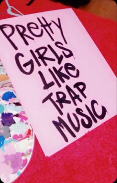 a sign that says pretty girls like trap music next to a skateboard with paint splattered on it