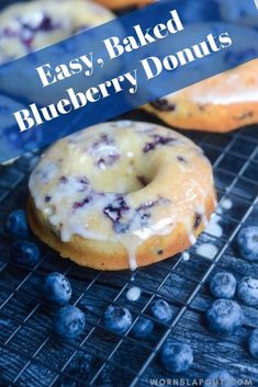 two blueberry donuts sitting on top of a cooling rack next to fresh blueberries