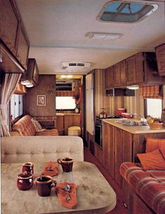 the interior of a motor home with wood paneling and couches, kitchen area