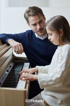 a father and daughter playing the piano together