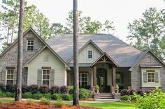 a house that is surrounded by trees and bushes in the front yard with landscaping around it