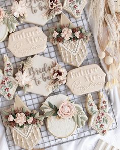 some cookies that are on top of a wire rack with flowers and leaves around them