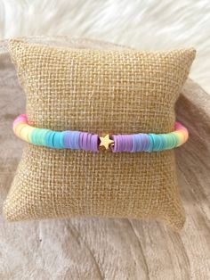 two bracelets with colorful beads and a star on the end are sitting on a pillow