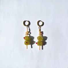 a pair of earrings is shown on a white surface, with one earring dangling from the other