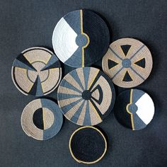 four woven coasters are arranged on a black tablecloth with yellow and blue designs