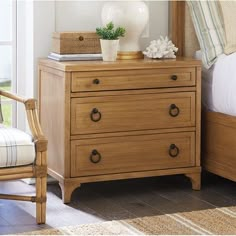 a bedroom scene with focus on the dresser and bed, along with an arm chair