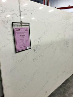 a white marble counter top with a sign hanging on it's side in a store