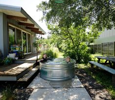 two children playing in an outdoor hot tub on the back deck of a small house