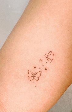 a small butterfly tattoo on the right arm and leg, with hearts coming out of it