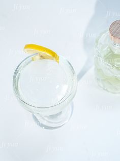 a small glass filled with water and a lemon slice on the rim next to it