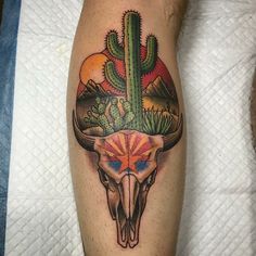 a tattoo on the leg of a man with a bull skull and cactus in it