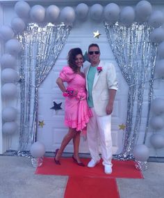 a man and woman standing in front of a door with balloons on the wall behind them