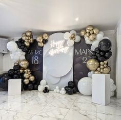 a room filled with balloons and black and gold decorations