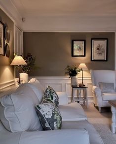 a living room with white furniture and pictures on the wall