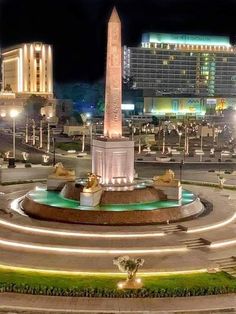 a large monument in the middle of a circular area with lights around it and buildings behind it