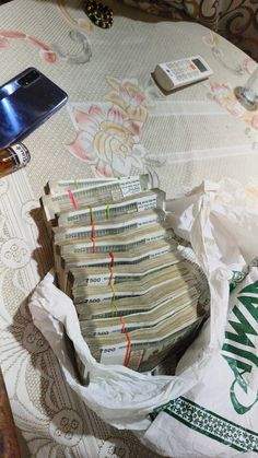 a pile of money sitting on top of a table next to a cell phone and other items