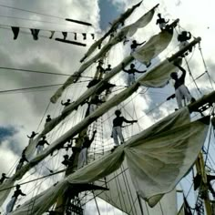 many people are climbing up and down the masts of a ship