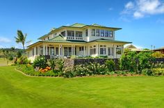 a large white house sitting on top of a lush green field next to a golf course