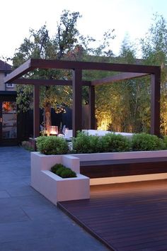 an outdoor area with benches and plants in the evening time, lit up by lights