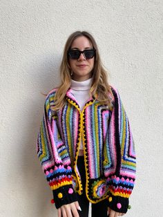 - Exquisite handcrafted crochet cardigan boasting vibrant hues of Blue, Purple, Pink, and Yellow. - Features a unique boho-chic design with playful pom-pom embellishments for a distinctive look. - Personalization options available for a cardigan that truly reflects your individuality. - Your satisfaction is key; enjoy precise craftsmanship with a promise of a 95% resemblance to the image. SIZES and MEASUREMENTS - The pictured item is suitable for sizes M. If you are unsure, please choose your regular size and give us your measurements! We'll make sure that the item is customized for you. PERSONALIZATION - Note that everything at Smyrna Collective is handmade individually by our creators. So we can do any Size / Design / Color customization that you like! Extra charge difference is applied Multicolor Granny Square Cardigan One Size, One Size Multicolor Granny Square Cardigan, Hand Knitted Multicolor Cardigan For Festivals, Hand Knitted Multicolor Festival Cardigan, One Size Multicolor Crochet Outerwear, One Size Multicolor Crochet Sweater, Handmade Multicolor Cardigan For Festival, Festival 2024, Boho Chic Design