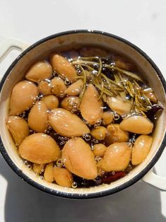 a pot filled with lots of food sitting on top of a white counter next to a spoon