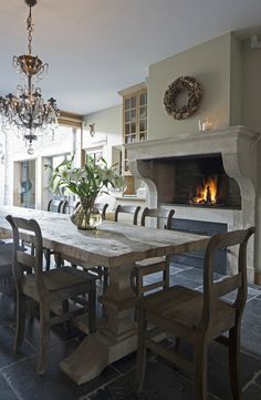 a dining room table and chairs with a fireplace in the background