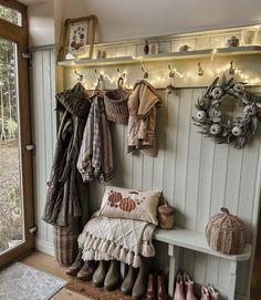 a coat rack filled with coats and shoes next to a wooden bench in front of a window