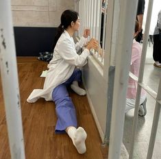 a woman sitting on the floor in front of a jail cell door with her legs crossed