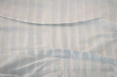 an unmade bed with white and blue sheets