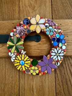 a colorful wreath made out of glass and buttons on a wooden door frame with a black ribbon