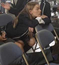 a woman sitting in a row of chairs with her arms crossed