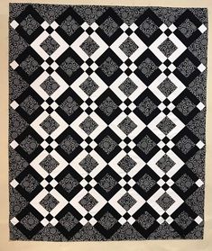 a black and white quilt hanging on a wall