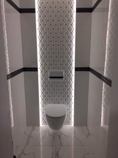 a white toilet sitting inside of a bathroom next to black and white tile wallpaper