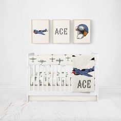 a white crib with two pictures on the wall above it and an airplane themed crib bedding set