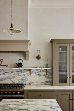 a kitchen with marble counter tops and cabinets in the corner, along with brass pulls