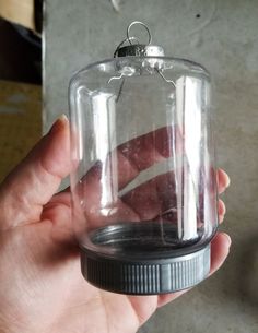 a hand is holding a glass bell jar