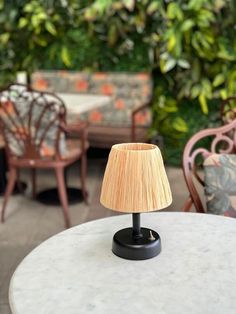 a lamp sitting on top of a table next to chairs and tables with plants in the background