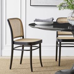 a dining room table with two chairs and a vase on top of the table next to it