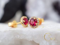 Gold ruby halo earrings, with a delicate yet eye capturing design. The stones have a stunning dark red color that gives you a mesmerizing effect with the accented stones all around. The Ruby is the birthstone of July. It represents love and passion. For centuries, this gem has been considered the king of all gems for its rarity, hardness (second only to a diamond), beauty and apparently mystical powers. Rubies have been the prized possession of emperors and kings throughout the ages, and to this Red Round Cluster Earrings For Wedding, Red Halo Design Earrings For Wedding, Ruby Earrings With Halo Design For Wedding, Ruby Halo Design Earrings For Wedding, Ruby Halo Earrings For Wedding, Wedding Ruby Earrings With Halo Design, Red Halo Setting Earrings For Wedding, Gold Ruby Earrings, Red Stud Earrings