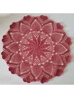 pink crocheted doily with white hearts on the center, sitting on a white surface