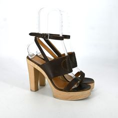 Hermes | Brown Strappy Wooden 'H' Logo Platform Heels Size: 39 Condition Is Pre-Owned. Used, Creasing On Vamp And Ankle Straps. Discoloration And Staining Around Midsole, As Well As The Ankle Straps. Signs Of Wear At Toe Box And Outsoles. Scuffing On Outsoles And Heel Tip. Details Open Round Toe Wooden Platform Heel Silver Tone Hardware Signature 'H" Logo Punctured Leather Made In Italy Measurements Platform Height" 1.5 In. Heel Height: 4 In. *Shoe Sizes May Vary Based On Designer And Style. Please Note That Pre-Owned Items Are Not New And Therefore Might Have Minor Imperfections. Measurements Are Approximate And The Product May Have Slight Disparities In Person. Designer Heels With Wooden Open Heel, Designer High Heels With Wooden Heel, Designer Heels With Wooden High Heel, Brown Platform Lace-up Heels, Brown Wooden Platform Heels, Brown Slip-on Platform Heels, Luxury Brown Sandals With 4-inch Heel, Brown T-strap Heels With Buckle Closure, H Logos