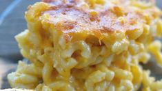 a stack of macaroni and cheese sitting on top of a wooden table next to a piece of bread