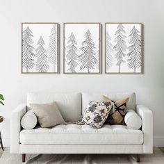 three black and white trees are hanging on the wall above a couch in a living room