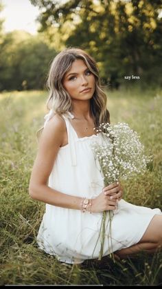 a woman sitting in the grass holding flowers