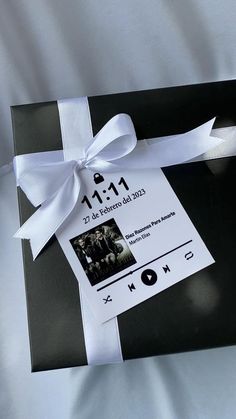 a black box with a white ribbon tied around it and some pictures on the side