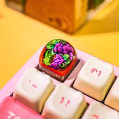 a pink computer keyboard with a small fruit decoration on it