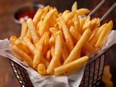 a basket filled with french fries on top of a wooden table