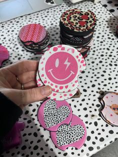 a person holding up a pink and white smiley face sticker on top of a table