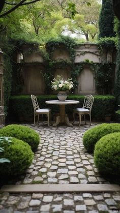 a table and two chairs in a small courtyard area with stone pavers flooring