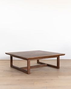 a wooden table sitting on top of a hard wood floor next to a white wall